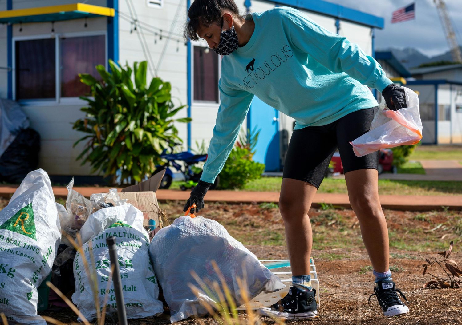 A woman cleans up trash in front of a home